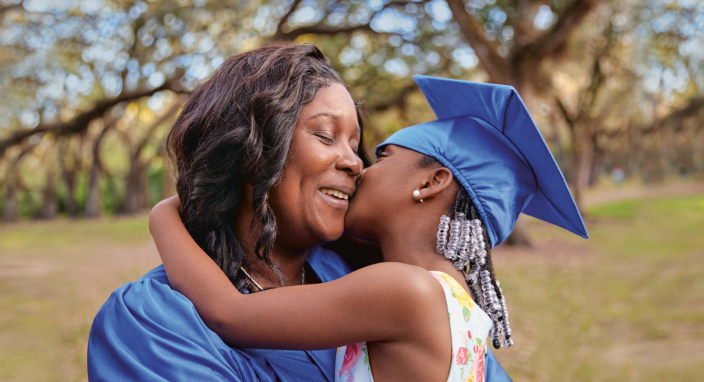 Picture of a mother wearing a cap and gown and holding her daughter
